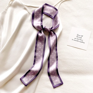 Détail d'un foulard en soie violet à pois noué comme accessoire sur une robe blanche chic