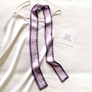 Gros plan détaillé d'un foulard en soie lilas à pois drapé sur une robe en satin blanc