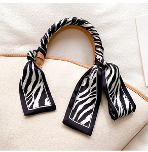 Detail of zebra print silk twilly scarf elegantly wrapped around a handbag leather handle