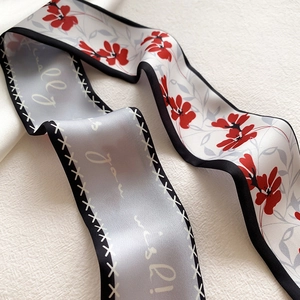 Vue macro détaillée du foulard en soie double face avec fleurs rouges et inscriptions