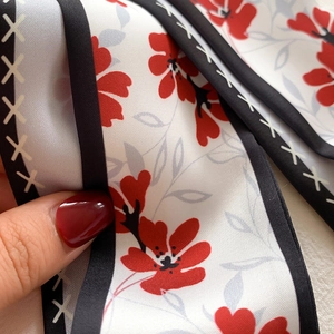 Détail macro du foulard twilly floral avec fleurs rouges et bordures à surpiqûres