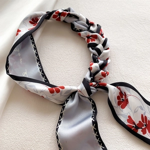 Gros plan d'un foulard en soie à fleurs avec bords noirs surpiqués et texture douce