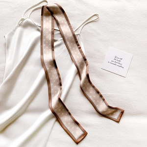 Gros plan du foulard en soie à pois champagne drapé sur une robe en satin blanc