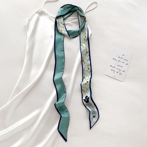 Gros plan du foulard en soie vert menthe et fleuri sur une robe en satin