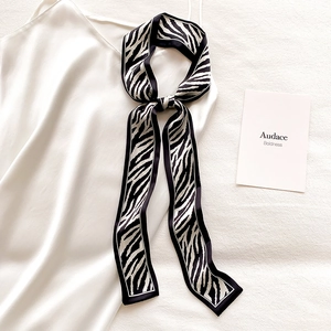 Detail of a zebra print satin skinny scarf paired with a white silk slip dress