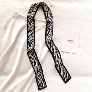 Close-up of zebra print narrow silk scarf on elegant white satin dress fabric