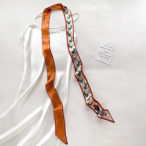 Détail d'un foulard en soie imprimé floral et lettres sur une robe blanche