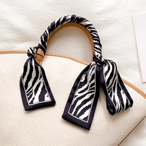 Chic zebra print narrow scarf tied on a beige canvas tote bag with brown leather handles
