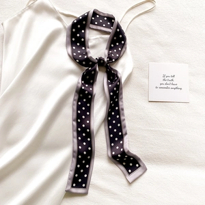 Détail d'un foulard étroit à pois noué avec élégance sur une robe en satin soyeux