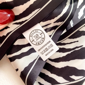 Detailed macro view of 100% polyester wash label on zebra print skinny scarf