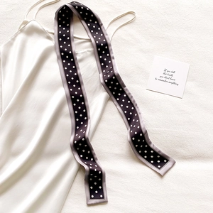 Détail d'un foulard en soie à pois associé à une robe nuisette en satin blanc nacré