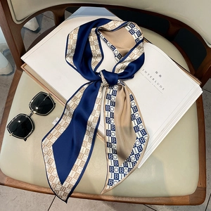 Elegant silk scarf with navy blue letter print next to black sunglasses on a magazine