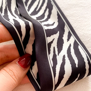 Detailed view of black and white zebra pattern silk scarf showing soft texture and sheen