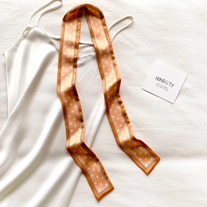 Gros plan d'un foulard en soie à pois roses avec des bordures noires et blanches