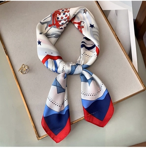 Detail of silk scarf tied in a knot featuring equestrian star pattern on gold-rimmed stand