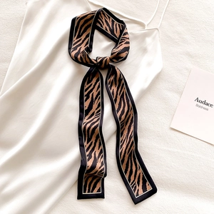 Close-up of leopard print skinny scarf tied on a white satin strap dress as a neck tie