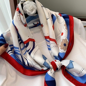 Close-up of silk neck scarf with star print tied over a shirt with floral brooch