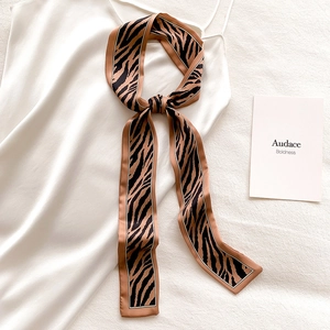 Detail of a zebra print skinny satin scarf tied elegantly on white silk clothing