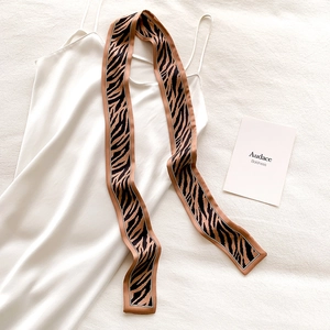 Detail of a narrow silk-like neckerchief with zebra and tiger animal prints on white silk