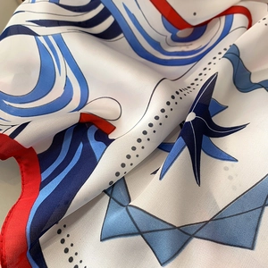 Close-up of nautical print silk scarf with red hand-rolled edges and twill texture