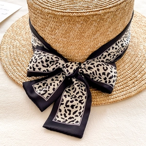 Elegant flat-top straw hat with leopard print silk ribbon and decorative bow detail