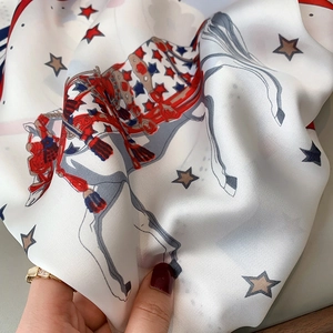 Detail of silk scarf with red stars and equestrian horse print in a light smooth texture
