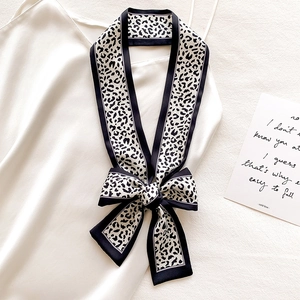 Detail of a leopard print skinny silk scarf tied in a bow on a white satin dress