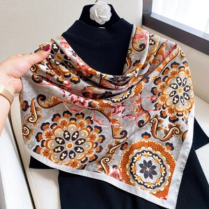Detail of elegant mandala floral silk scarf with orange and grey patterns on black clothing