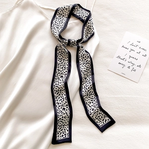 Close-up of leopard print twilly silk scarf tied on a white satin strap dress