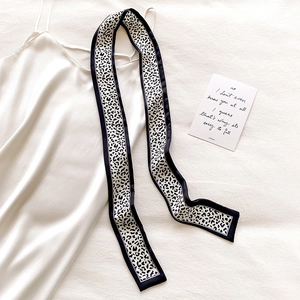 Detail of elegant leopard print silk twilly scarf styled with a white velvet camisole top