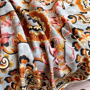 Close-up of soft printed scarf fabric with vintage orange paisley floral patterns