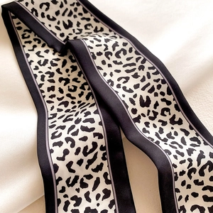 Macro shot of silk leopard print skinny scarf featuring elegant black borders and soft texture
