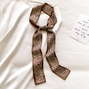 Macro detail of leopard print skinny silk scarf tied in a bow on a satin dress