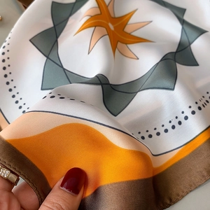 Detail of silk satin scarf showing geometric star patterns and glossy fabric texture