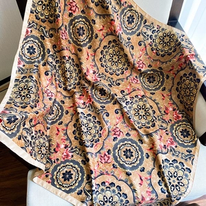 Detail of a large silk-like square scarf with blue mandala prints on bronze fabric