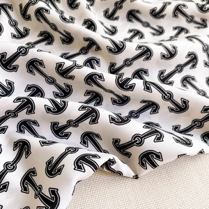 Close-up of white textile fabric with black anchor print showing smooth texture and drapes
