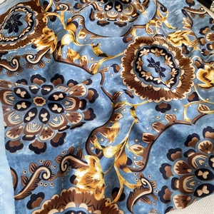 Macro shot of dark blue silk scarf with detailed vintage golden floral mandala patterns