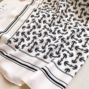 Detail of white silk scarf showing black anchor chain print and soft fabric texture