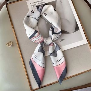 Detail view of a geometric star pattern silk scarf tied in a bow on a gold tray