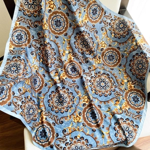 Detail of floral print silk scarf with blue and gold baroque pattern on a chair