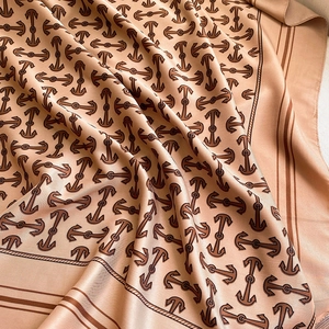 Detailed macro view of champagne silk scarf with nautical anchor and chain patterns