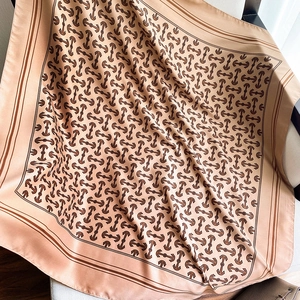 Detail of silk-like square scarf with anchor chain print draped over a chair