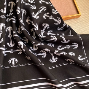 Macro detail of silk-like scarf featuring anchor-style patterns and contrast white stripes
