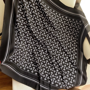 Close-up of anchor print on a black silk-like square scarf draped on furniture