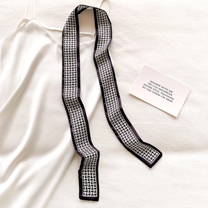 Detailed view of a black and white houndstooth skinny scarf on a satin dress