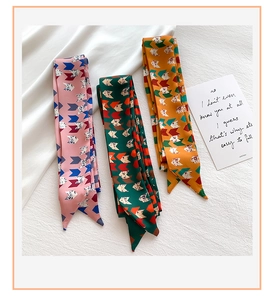 Detailed view of three colorful geometric pattern silk scarves on a white fabric background