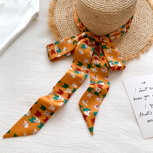 Straw sun hat with orange geometric silk scarf accent and elegant floral patterns