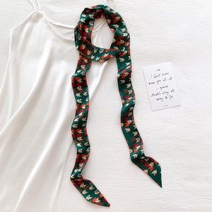 Elegant emerald green silk twilly scarf with geometric fox pattern on white dress