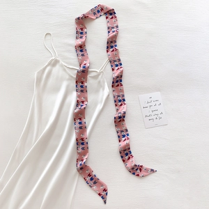 Detail of pink geometric pattern silk scarf paired with a white satin strap dress