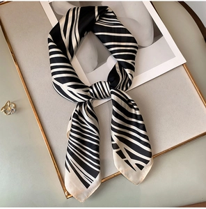 Close-up of zebra pattern silk scarf knotted on a grey board with gold ring detail
